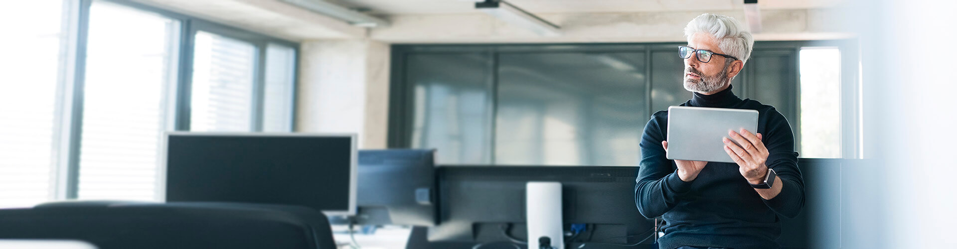 Momento Digitalizar mis gestiones - Hombre de mediana edad con gafas y camisa negra trabajando en su oficina con una tablet pensando en digitalizar las gestiones de su empresa Momento Digitalizar mis gestiones - Hombre de mediana edad con gafas y camisa negra trabajando en su oficina con una tablet pensando en digitalizar las gestiones de su empresa