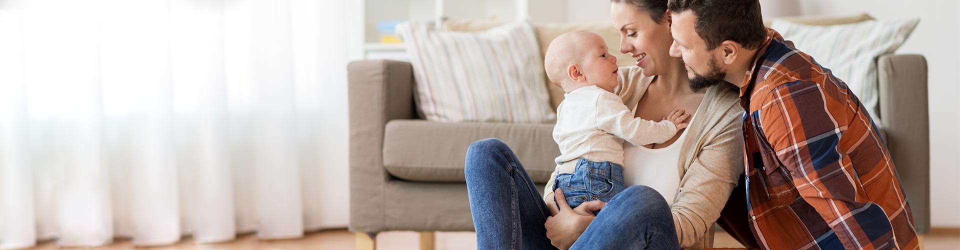 Seguros para Particulares - Familia con bebe sentados en el suelo del salon de su casa jugando Seguros para Particulares - Familia con bebe sentados en el suelo del salon de su casa jugando
