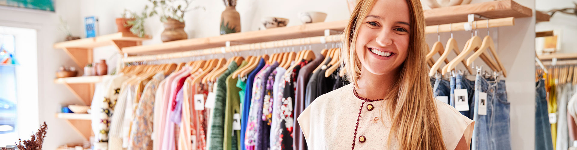 Tu negocio online - Autónoma en su tienda de ropa sonriendo con una tablet en la mano utilizando infomail Tu negocio online - Autónoma en su tienda de ropa sonriendo con una tablet en la mano utilizando infomail