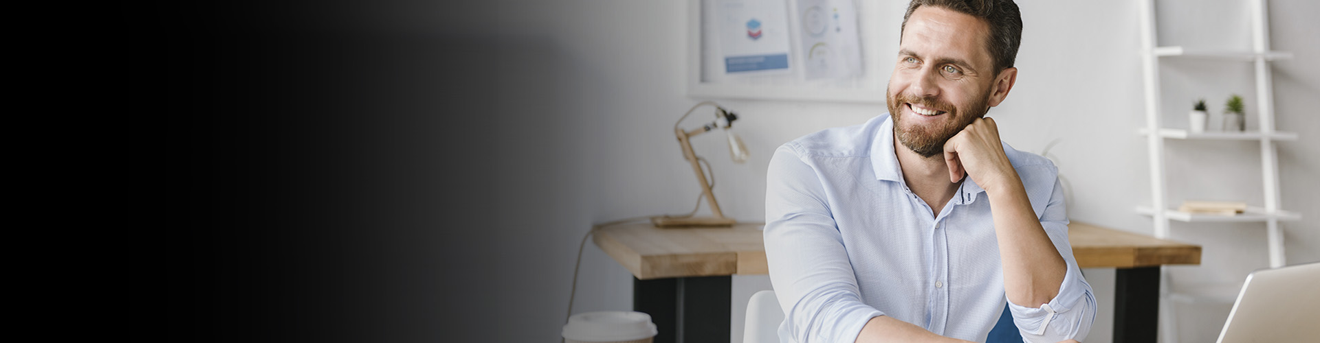 Cuentas Autónomos - Hombre de negocios con barba y camisa blanca sonriendo mientras trabaja frente su portátil Cuentas Autónomos - Hombre de negocios con barba y camisa blanca sonriendo mientras trabaja frente su portátil