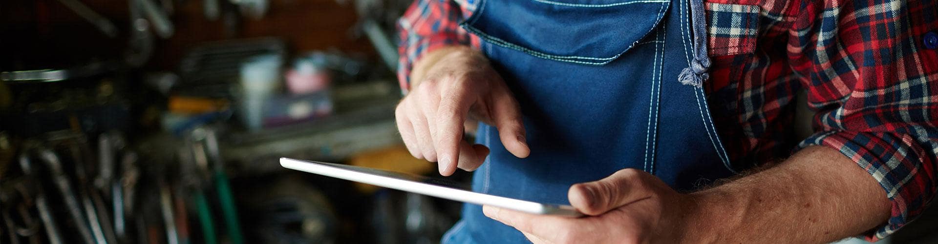Cobros Autónomos - Un hombre con camisa de cuadros está utilizando su tableta digital. Cobros Autónomos - Un hombre con camisa de cuadros está utilizando su tableta digital.